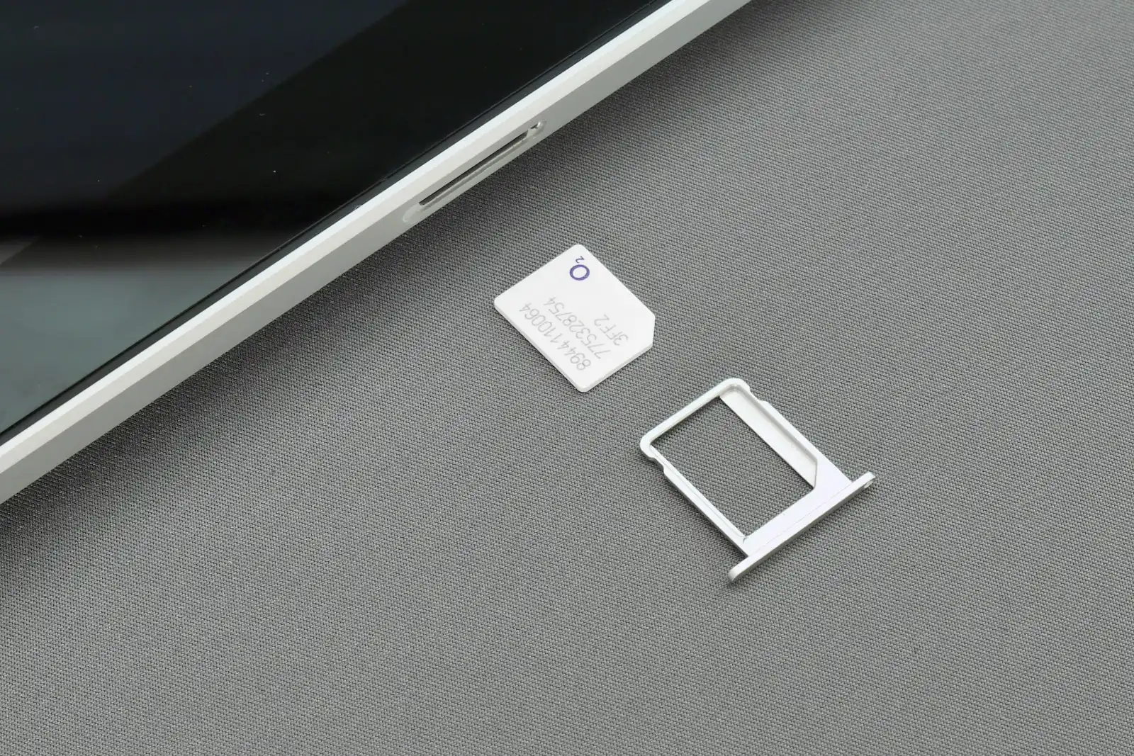 Smartphone next to a nano SIM card and ejected SIM tray, illustrating the eSIM versus physical SIM card choice for Korea