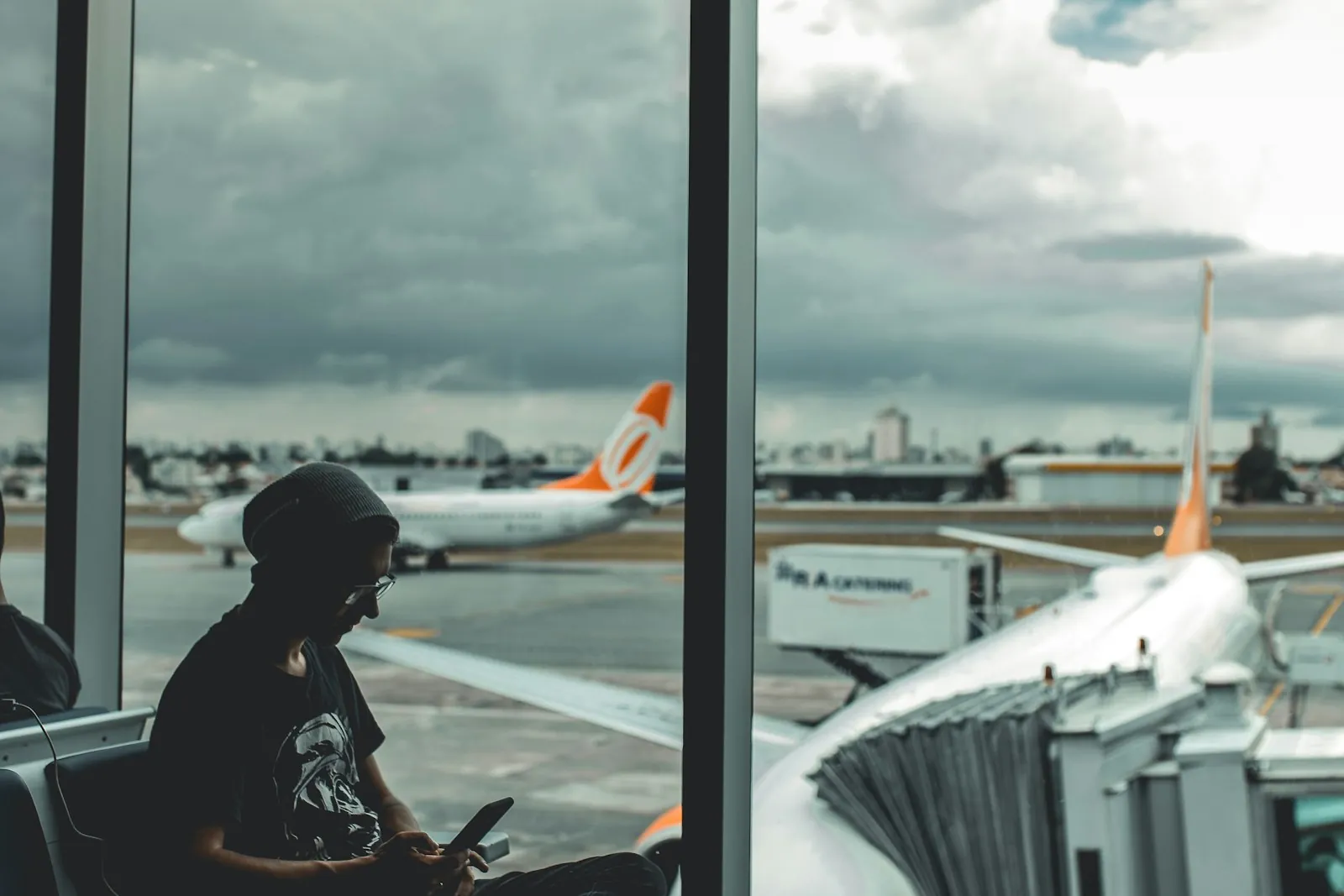 Traveler checking a smartphone at an airport gate with a plane on the tarmac, comparing a Korea SIM at Incheon Airport with an eSIM bought online