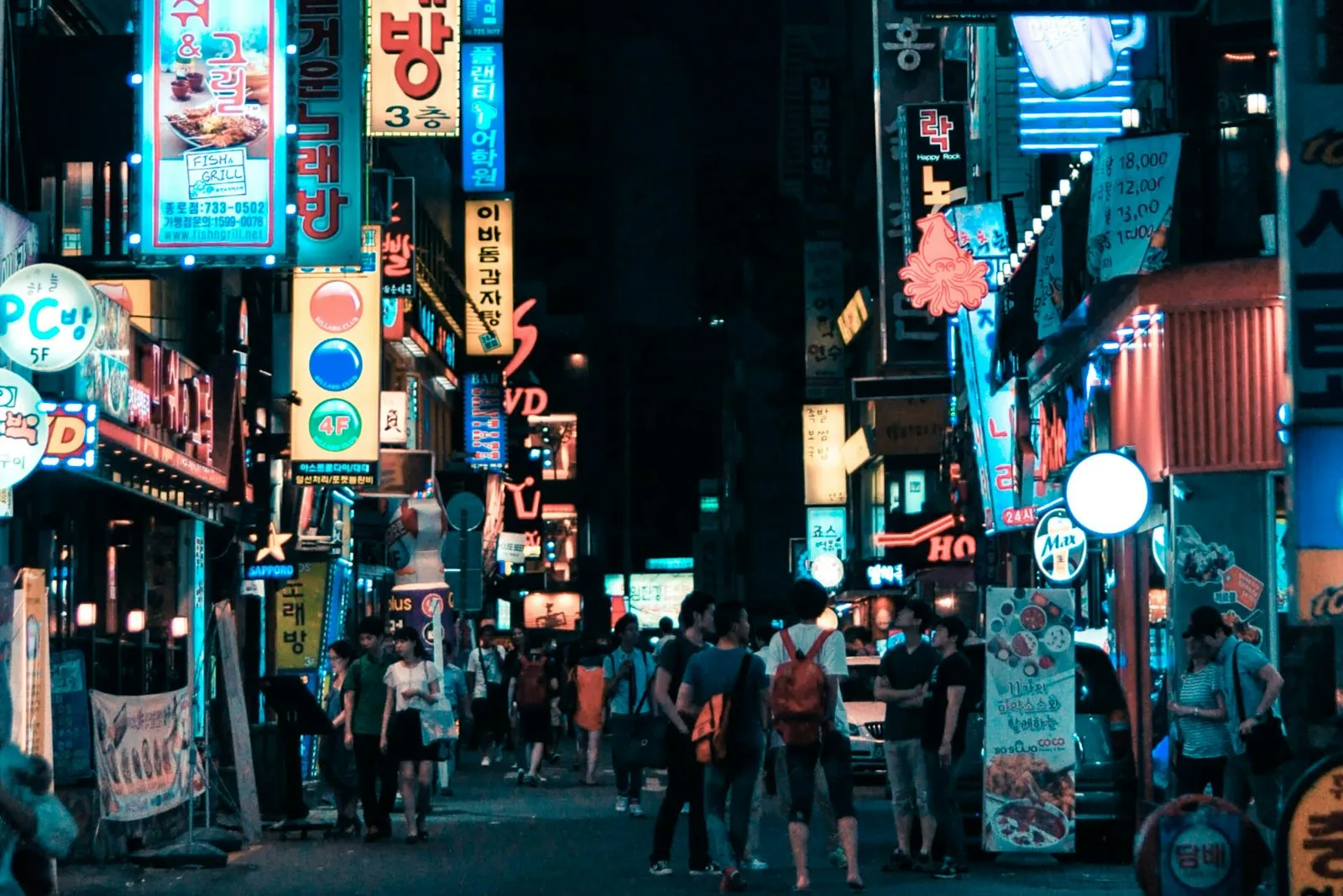Neon Hangul signs on a busy Seoul street at night, illustrating using a Korea travel SIM card or data eSIM after landing in Seoul