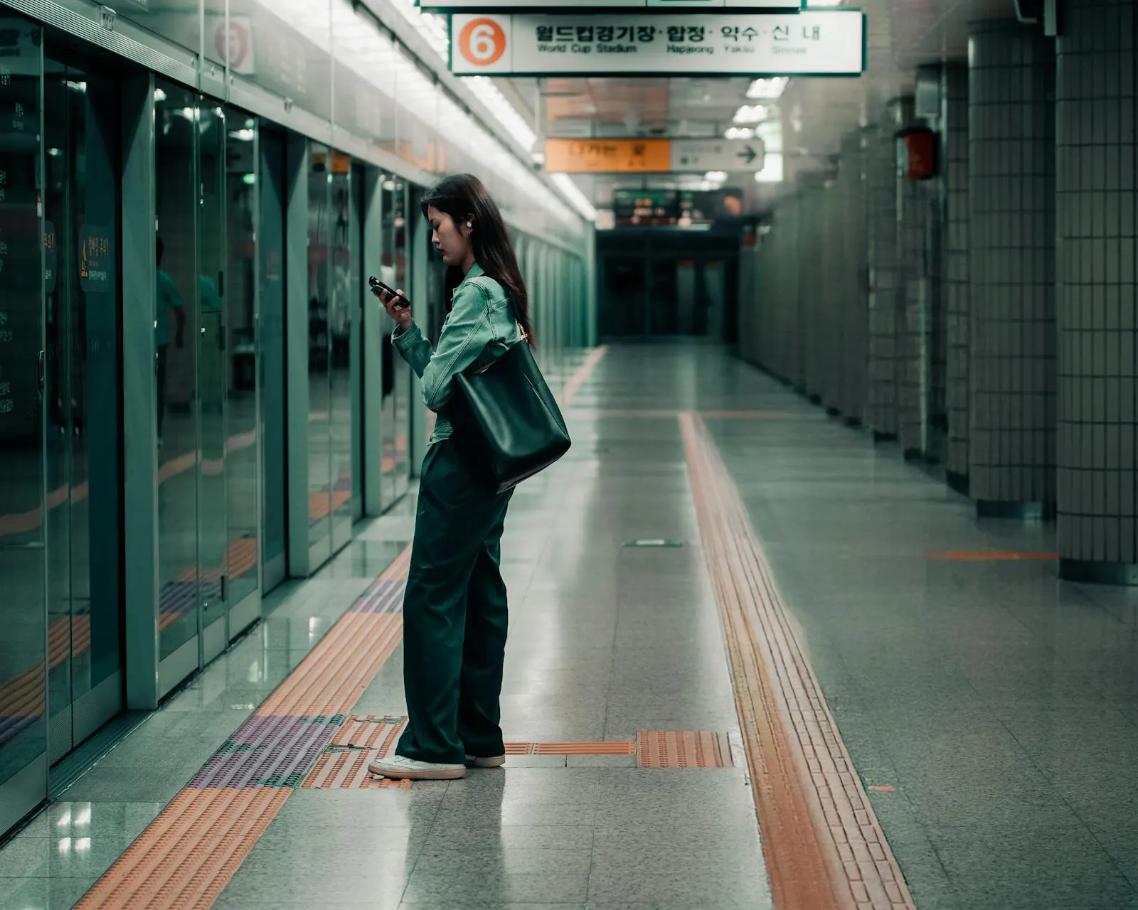 A traveller checking their phone on a Seoul subway platform