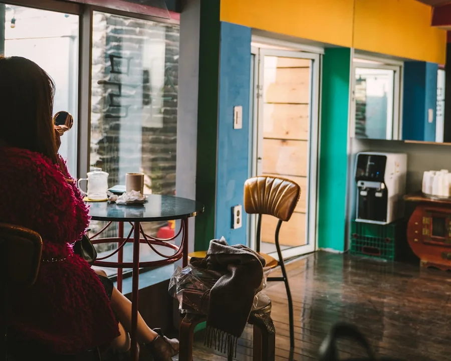 A teacher settling in with coffee by the window of a warm Seoul cafe